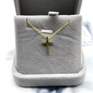 Elegant gold cross pendant necklace displayed in a premium grey velvet jewelry gift box