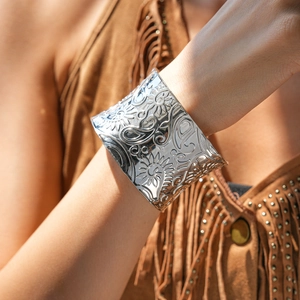 Macro shot of silver embossed cuff bracelet with intricate floral carvings and metal textures