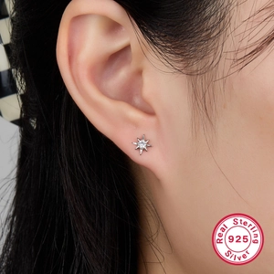 Close-up of S925 sterling silver star stud earring with sparkling cubic zirconia on ear