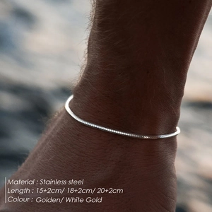 Close-up of a silver stainless steel snake chain bracelet worn on a wrist by the water