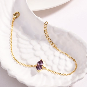 Detail of gold chain bracelet featuring two purple heart-shaped stones on white decor