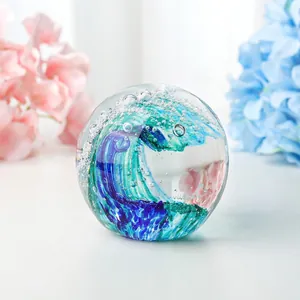 Artistic ocean wave glass paperweight with blue vortex design and air bubbles