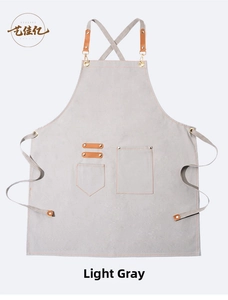 Detail of light grey canvas apron with brown leather straps and metal buckles