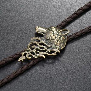 Macro view of bronze wolf head emblem on woven leather bolo tie with vintage finish