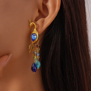Detail of vintage peacock earrings with blue gemstones and colorful beaded tassels