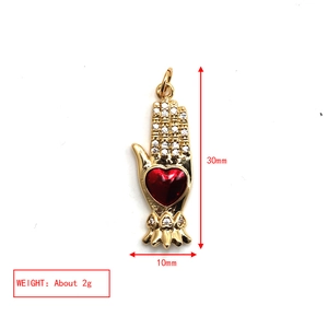Golden Hamsa hand pendant with red heart gemstone including 30x10mm size and 2g weight details