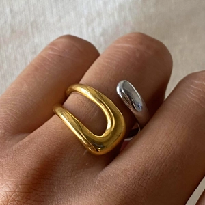 Primo piano di eleganti anelli in acciaio inossidabile a U dorati e argento lucido su un modello
