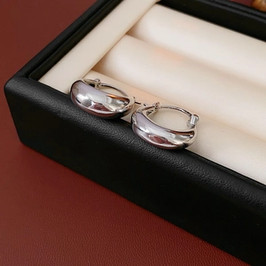 Close-up of silver U-shaped metal earrings displayed in a luxury black leather jewelry box