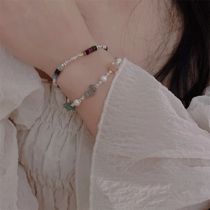 Detail of layered bracelets with natural stones, white pearls and silver beads on wrist
