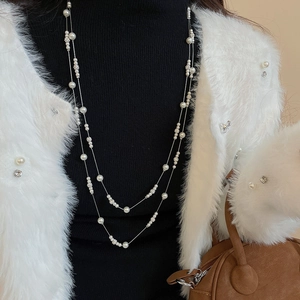 Close-up of elegant double-layered pearl necklace with crystal accents on a black sweater