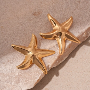Detailed view of gold starfish stud earrings on a textured natural stone background