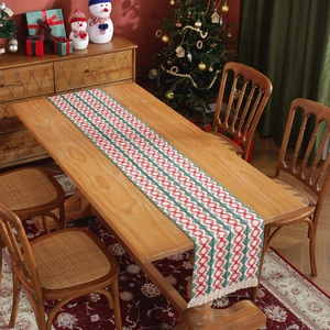 Christmas cotton table runner with red and green stripe weave and fringe on wooden table