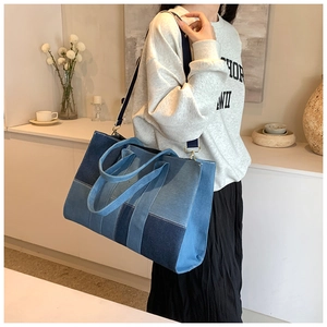 Detail of color-block denim tote bag with gold hardware on a minimalist background