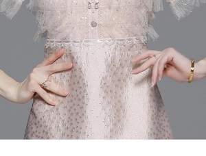Detailed close-up of pink sequin lace embroidery and pearl button on the luxury dress