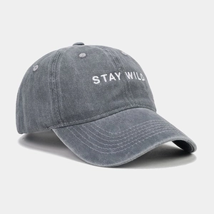 Close-up of Stay Wild white embroidery on washed gray denim baseball cap texture