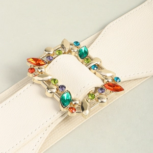 Close-up of cream elastic leather belt with gold square buckle and colorful gemstones