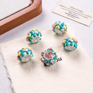 Detailed macro view of five hand-painted resin floral beads on a beige linen fabric background
