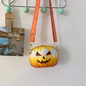 Detail of pumpkin-shaped crossbody bag with smiling face pattern and floral strap