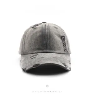 Front detail of deep grey washed denim baseball cap with heavy distressed ripped effects