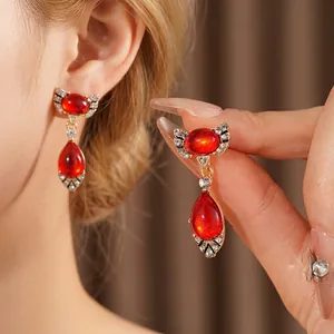 Vintage gold-plated drop earrings with red oval crystals and sparkling bow detail