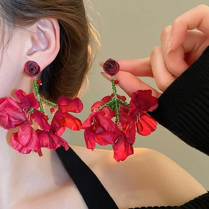 Close-up of fabric red rose tassel earring with green beaded stems on a model