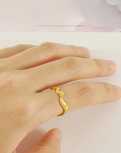 Gros plan d'une bague en acier inoxydable plaqué or 18k ondulée portée au doigt