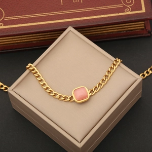 Detail of pink cat-eye stone necklace with golden cuban chain on a jewelry box