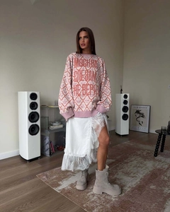 Detail of pink knit sweater with geometric patterns paired with a lace skirt