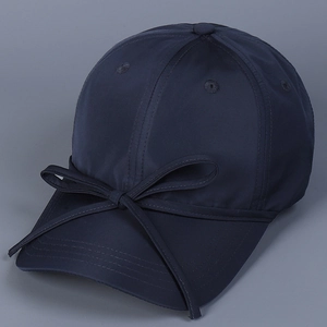 Close-up of navy blue satin baseball cap with delicate bow detail and fine stitching