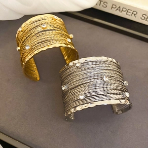 Detail of multi-layer gold and silver bangles with sparkling crystals on grey background
