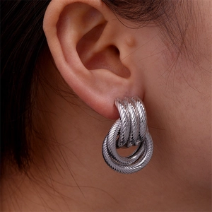 Detailed macro view of silver twisted rope textured triple hoop earrings worn on ear