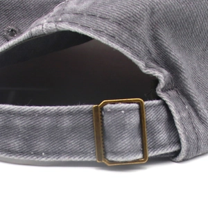 Close-up of adjustable bronze buckle and washed grey denim fabric on the baseball cap
