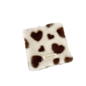 Square plush heart coaster with cow print and brand label for coffee table decor