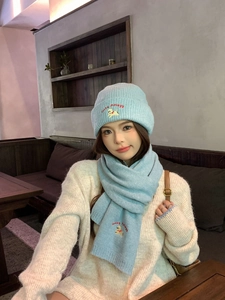 Detail of light blue knitted hat and scarf set with cute dog embroidery for winter