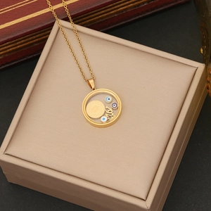 Detail of gold evil eye necklace pendant with Ask lettering on beige jewelry box