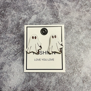 Detail shot of white acrylic ghost earrings for Halloween on a grey textured background