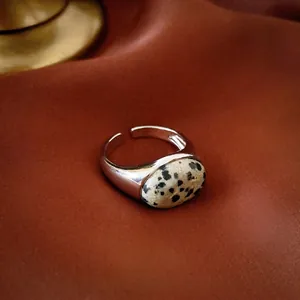 Makroaufnahme von silbernem verstellbarem Ring mit ovalem gepunktetem Stein auf Satin