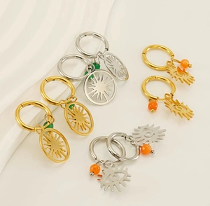 Detail of bohemian hoop earrings with sun and evil eye charms in gold and silver