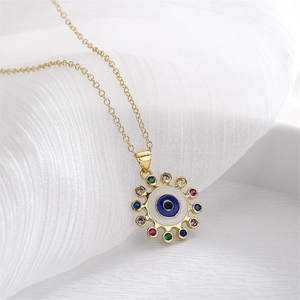 Close-up of golden Evil Eye necklace with colorful zircons on white fabric