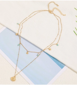 Detail of double-layer gold shell necklace with turquoise beads and lobster clasp