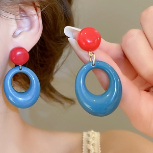 Gros plan des boucles d'oreilles boules rouges et pendentifs ovales en résine bleue