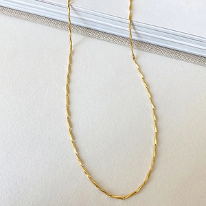 Detailed view of layered gold-tone twist rope chain on a clean white background