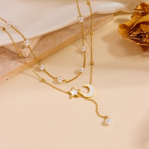 Detailed close-up of double-layered gold necklace with pearls and celestial star moon charms