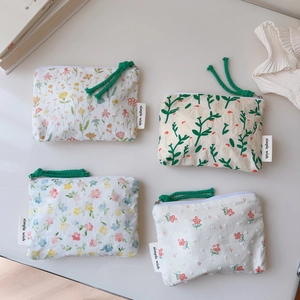 Macro detail of four floral cotton mini pouches with textured fabric and green zipper pulls
