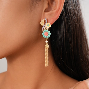 Détail de boucle d'oreille fleurie avec rose rose, marguerite verte et pompon doré