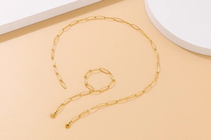 Detail of minimalist gold oval link necklace and bracelet set on geometric background