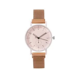 Détail d'une montre à cadran rose mat avec aiguilles coeur et bracelet en maille