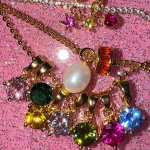Golden necklace with colorful round zircon charms and white pearl on pink glitter background