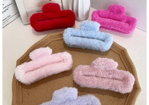 Detailed view of assorted fluffy plush hair claws in soft pastel colors in a tray