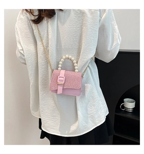 Detail of pink pearl handle handbag with shimmering sequin texture and golden chain